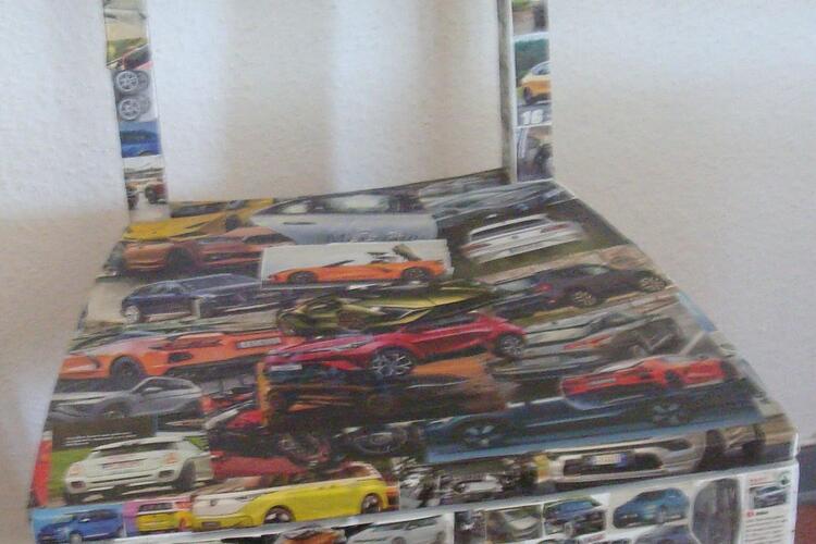 Stuhl mit Autos aus Zeitungschriften beklebt